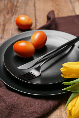 Table setting with Easter eggs, tulip flowers and cutlery on wooden backgroundの写真素材