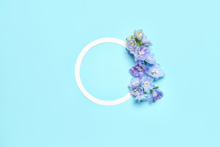 Blank round frame and beautiful delphinium flowers on blue backgroundの写真素材