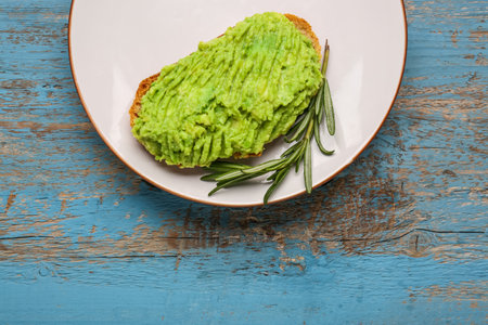Plate with delicious avocado toast and rosemary on blue wooden backgroundの写真素材
