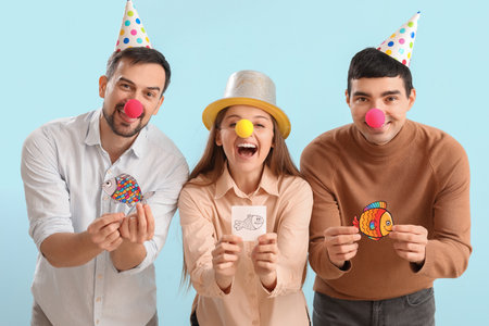 Business colleagues with clown noses and paper fishes on blue background. April Fools' Day celebrationの写真素材