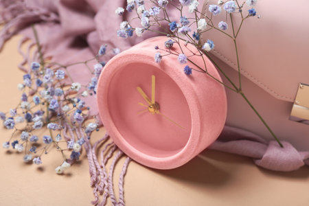 Alarm clock, gypsophila flowers and female accessories on color background, closeup