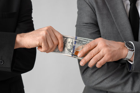 Businessman giving bribe on gray background, closeupの写真素材