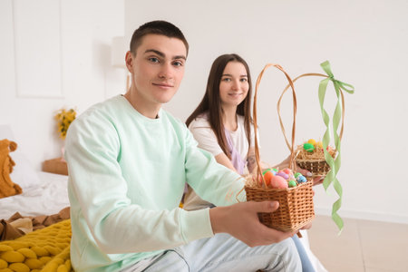 Happy young couple with baskets of Easter eggs in the bedroomの写真素材