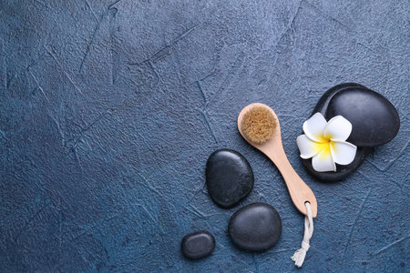 Composition with massage brush, spa stones and flower on dark color background