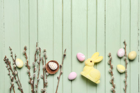 Composition with willow branches, Easter eggs and toy bunny on color wooden backgroundの写真素材
