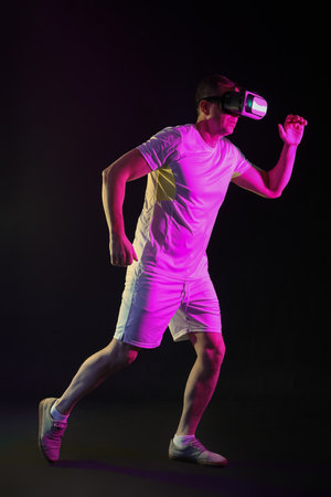 Sporty mature man in VR glasses running on dark background