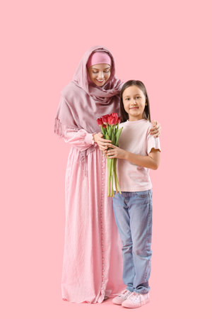 Little girl with tulips and her Muslim mother on pink backgroundの写真素材