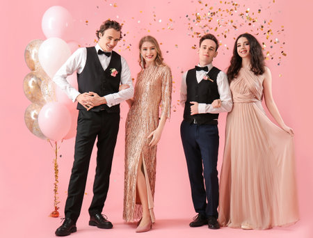 Beautiful couples dressed for prom on pink backgroundの写真素材