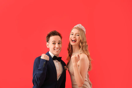 Happy young couple dressed for prom on red backgroundの写真素材