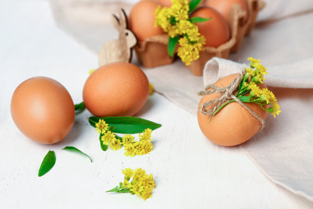 Easter eggs and goldenrod flowers on white wooden background