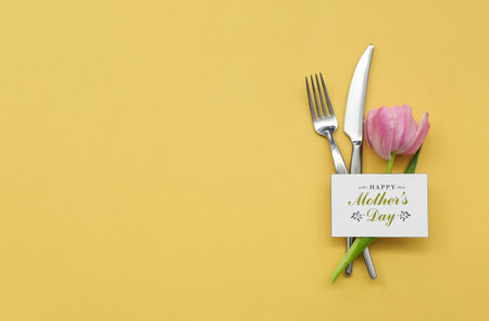 Greeting card with text HAPPY MOTHER'S DAY, cutlery and tulip flower on yellow backgroundの写真素材