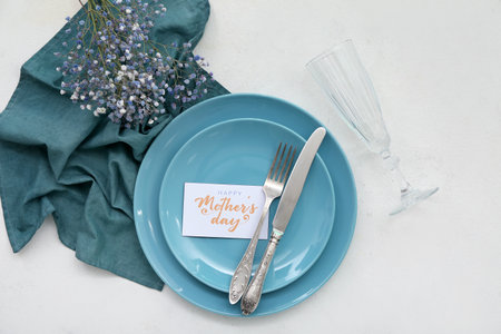 Stylish table setting with gypsophila flowers for Mother's Day celebration on light backgroundの写真素材
