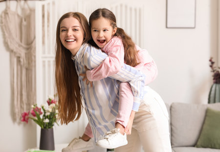Cute little girl with her mom at home on Mother's Dayの写真素材