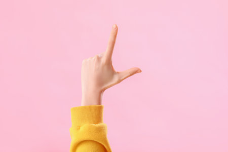 Young woman showing loser gesture on pink backgroundの写真素材