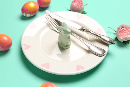 Table setting with Easter rabbit, eggs and flowers on mint background, closeupの写真素材
