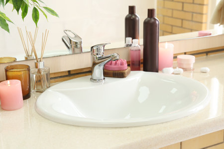 Table with ceramic sink, burning candles and bath suppliesの写真素材