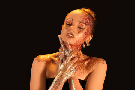 Beautiful young woman with glitter makeup on dark backgroundの写真素材