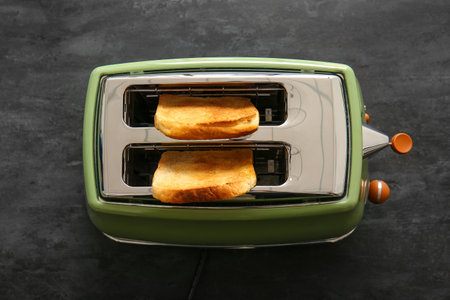 Modern toaster with crispy bread slices on black backgroundの写真素材