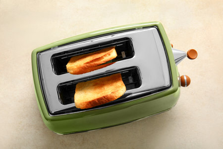 Modern toaster with crispy bread slices on beige backgroundの写真素材