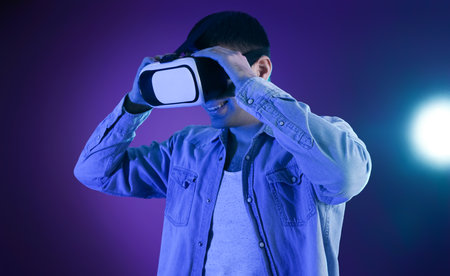 Young man using VR glasses on dark color backgroundの写真素材