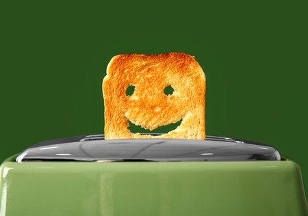 Funny slice of bread in modern toaster on green backgroundの写真素材