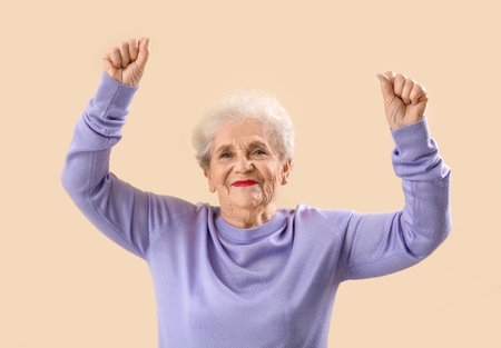 Senior woman in lilac sweater dancing on beige backgroundの写真素材