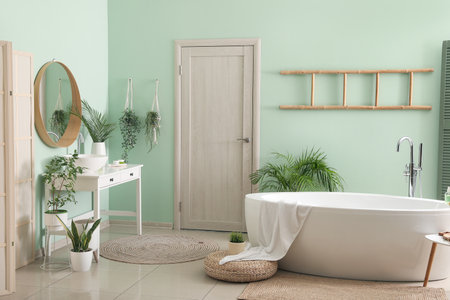 Interior of bathroom with modern bathtub, ceramic sink and houseplants near green wallの写真素材