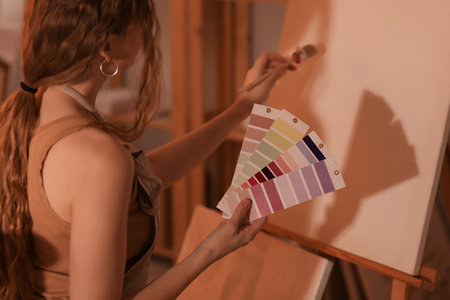 Female artist with color palettes drawing in workshop, closeupの写真素材