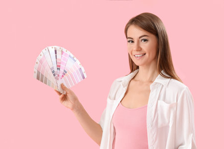 Beautiful woman with paint palette colors on pink backgroundの写真素材