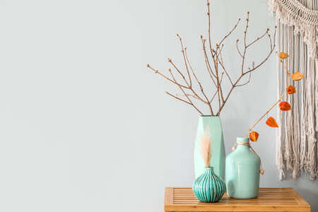 Vases with tree branches on wooden table near light wallの写真素材