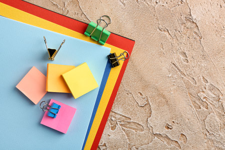 Paper sheets, sticky notes and binder clips on color background, closeup