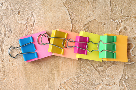 Sticky notes with colorful binder clips on color background