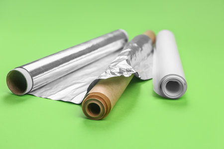 Rolls of aluminum foil and baking paper on green backgroundの写真素材