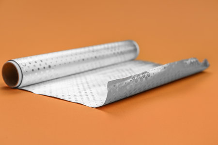 Roll of aluminum foil on orange background