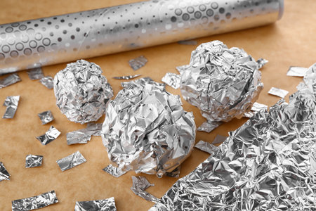 Crumpled balls and pieces of aluminum foil on color background, closeupの写真素材