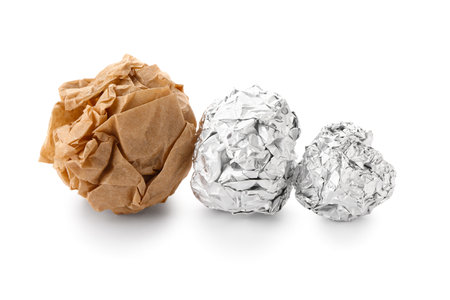 Crumpled balls of aluminum foil and baking paper on white backgroundの写真素材