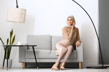 Beautiful Muslim woman sitting on sofa at homeの写真素材