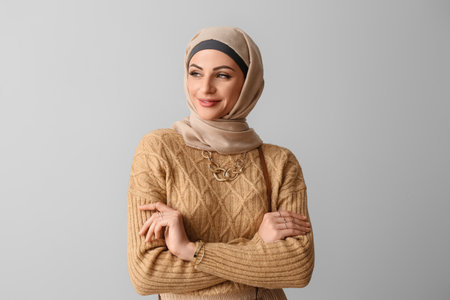 Stylish Muslim woman in beige hijab on light backgroundの写真素材