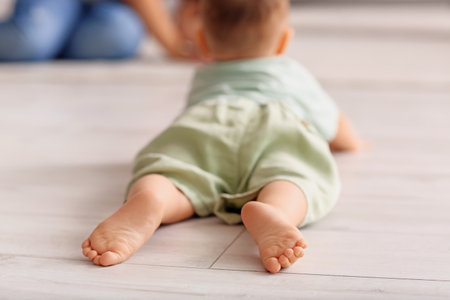 Small feet of baby boy lying on floor at home, closeupの写真素材
