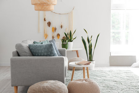 Interior of light living room with green houseplants, sofa and tables