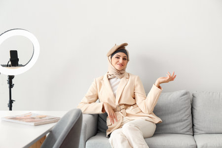 Stylish Muslim woman sitting on sofa at homeの写真素材