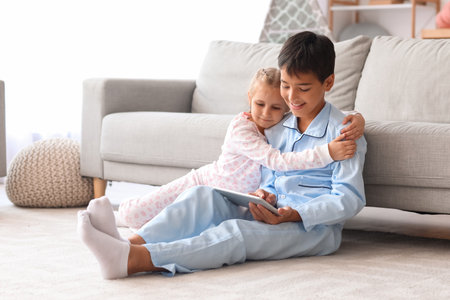 Little boy with his sister watching cartoons on tablet computer at homeの写真素材