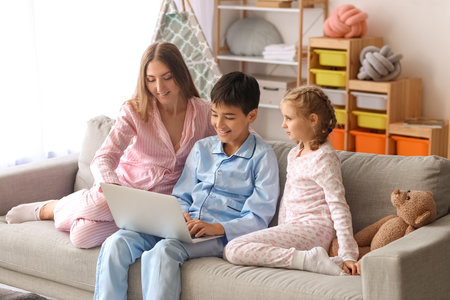 Mother with her little children watching cartoons on laptop at homeの写真素材