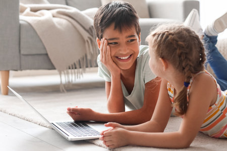 Little boy and girl watching cartoons on laptop at homeの写真素材