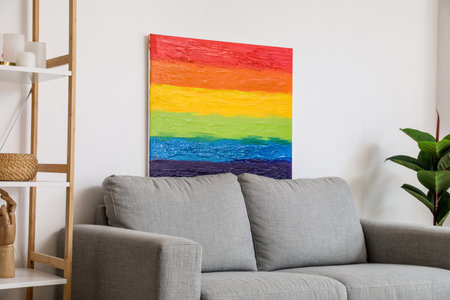Painting of LGBT flag on sofa near light wallの写真素材