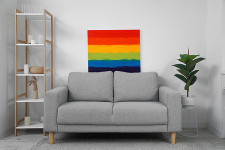 Sofa with painting of LGBT flag and shelving unit near light wallの写真素材