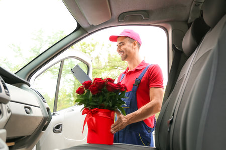 Delivery man with beautiful flowers near car outdoorsの写真素材