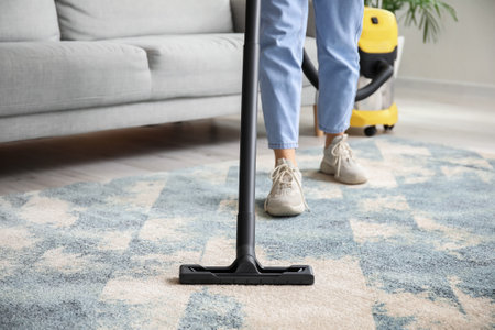 Woman cleaning beautiful carpet in living roomの写真素材