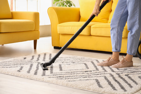 Woman cleaning beautiful carpet in living roomの写真素材