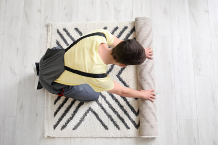 Man rolling carpet on floor in roomの写真素材